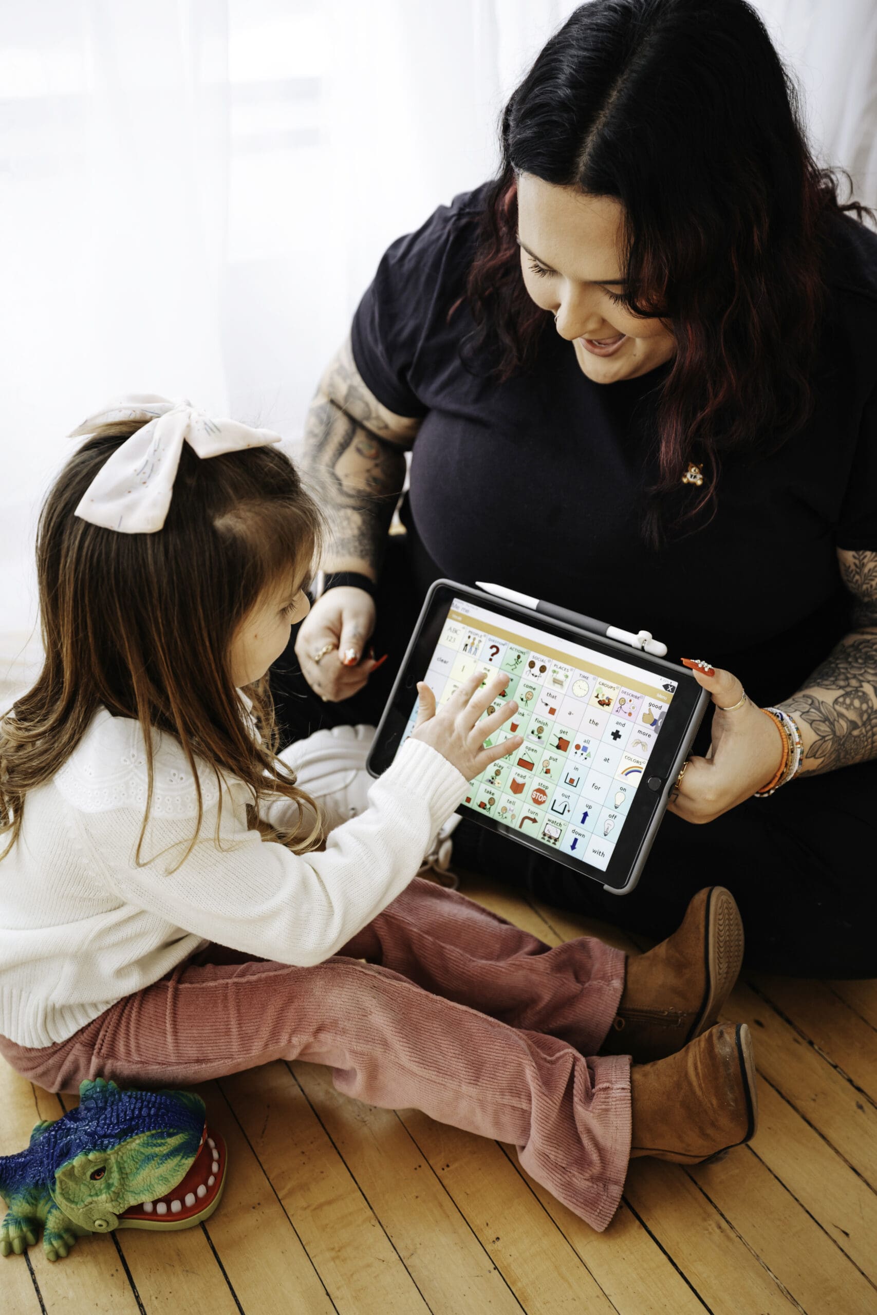 A female SLP uses an AAC device with a little girl