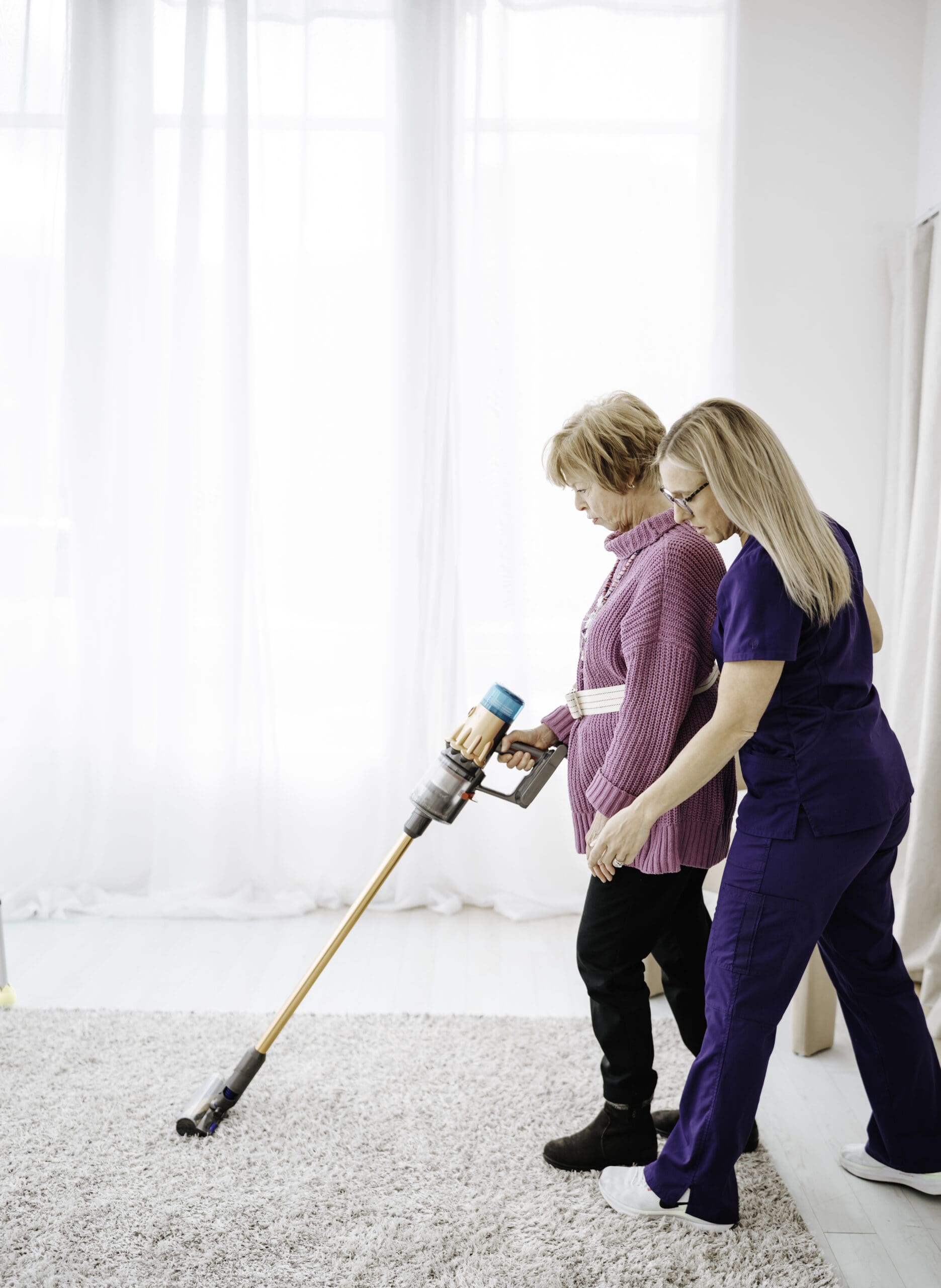 An OT helping a patient vacuum